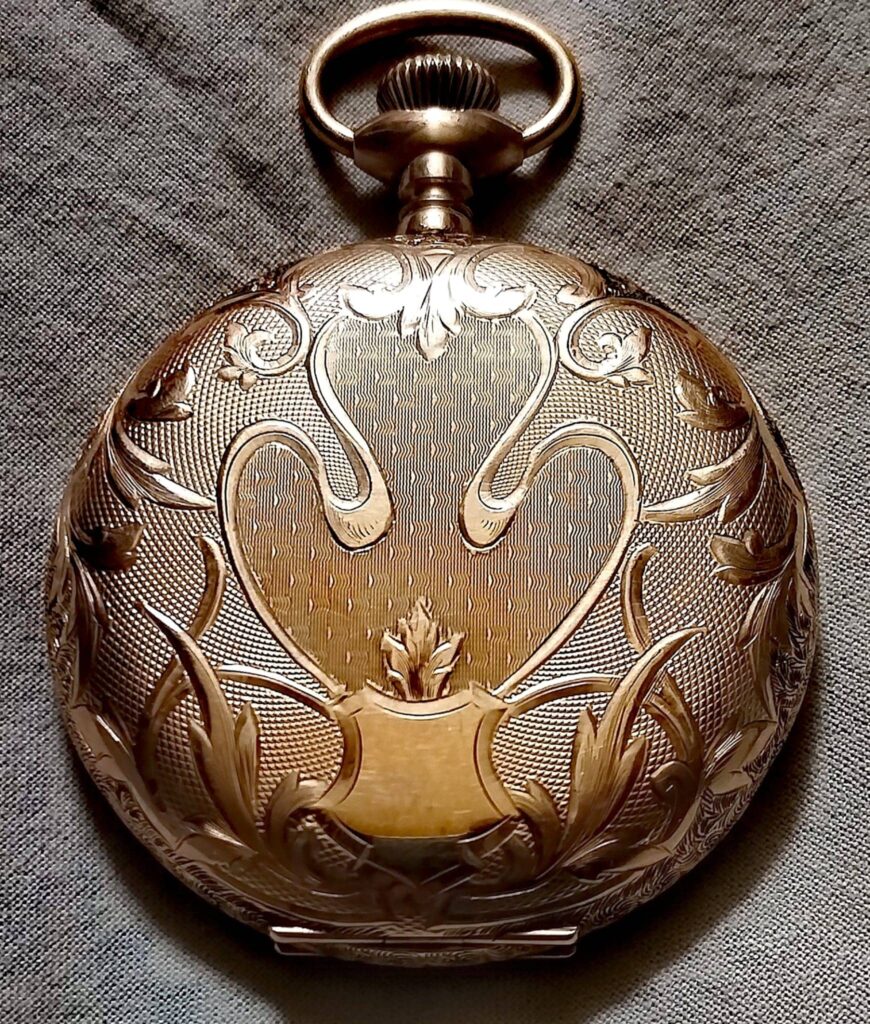 Reloj de bolsillo de oro con la tapa grabada a mano